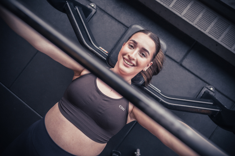 Glad tjej på gymmet som kör bänkpress