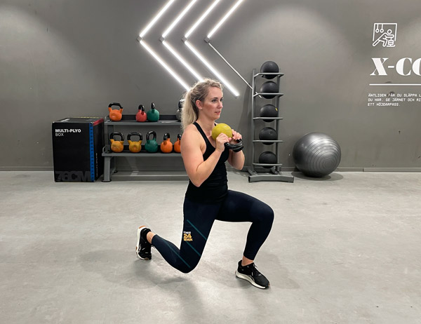 Kvinna gör utfall fram och bak med kettlebell