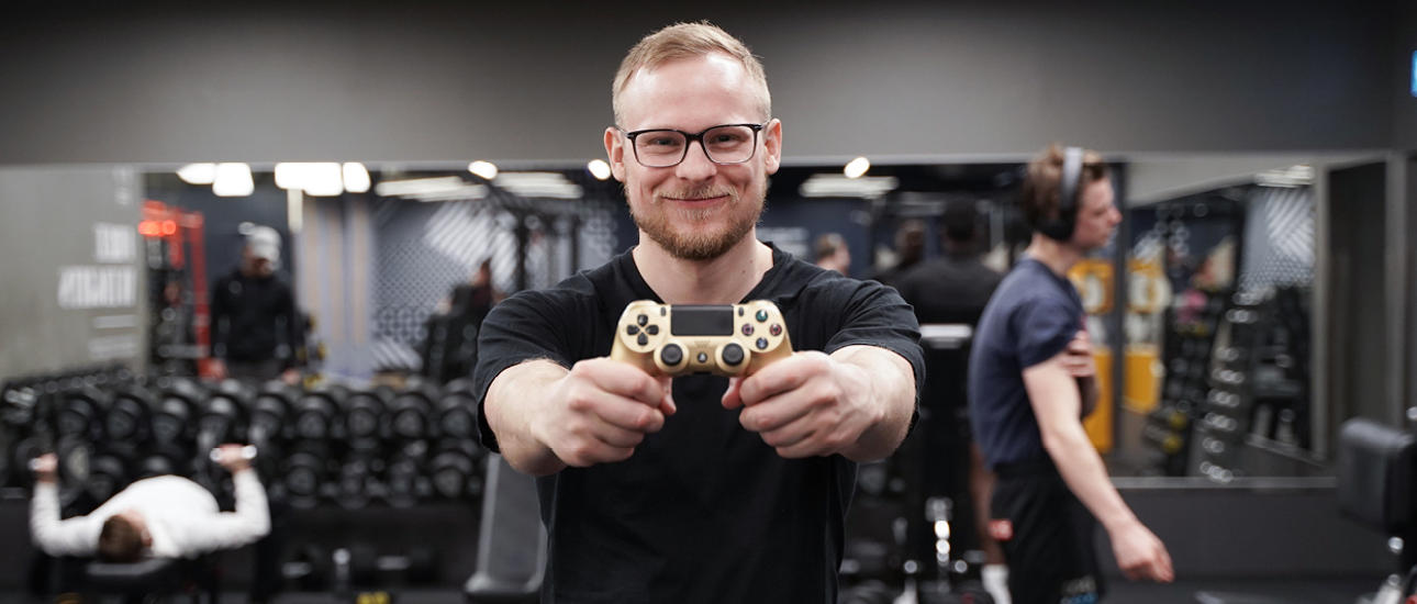 Man på gymmet håller PS4 kontroller