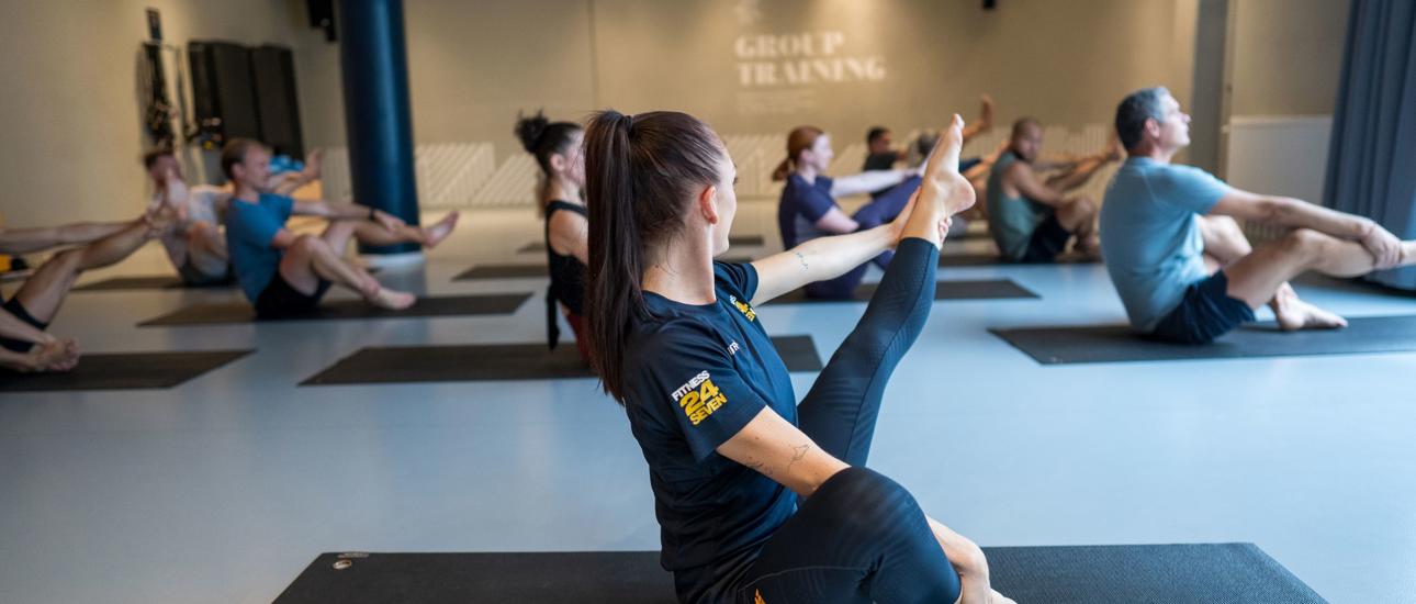 Pilates gruppträning på Fitness24Seven med instruktör i förgrunden med rakt ben 