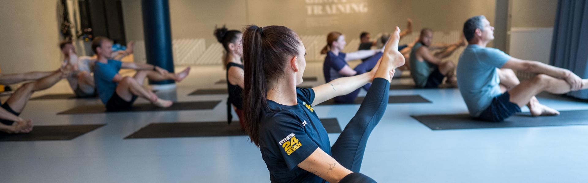 Pilates gruppträning på Fitness24Seven med instruktör i förgrunden med rakt ben